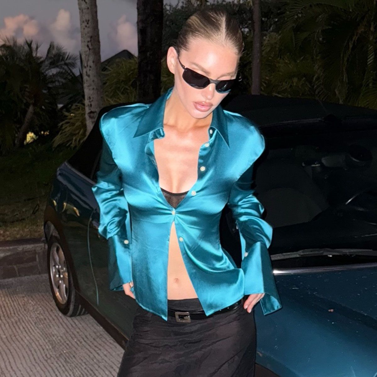 Woman in blue satin shirt and low-rise black skirt