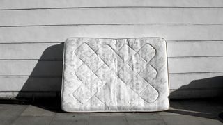 A mattress leant against an outside wall