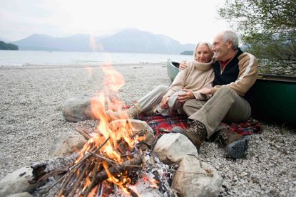 older couple sitting by a campfire