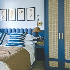 Light blue painted bedroom with a dark blue headboard behind the bed, and dark blue wardrobe next to it