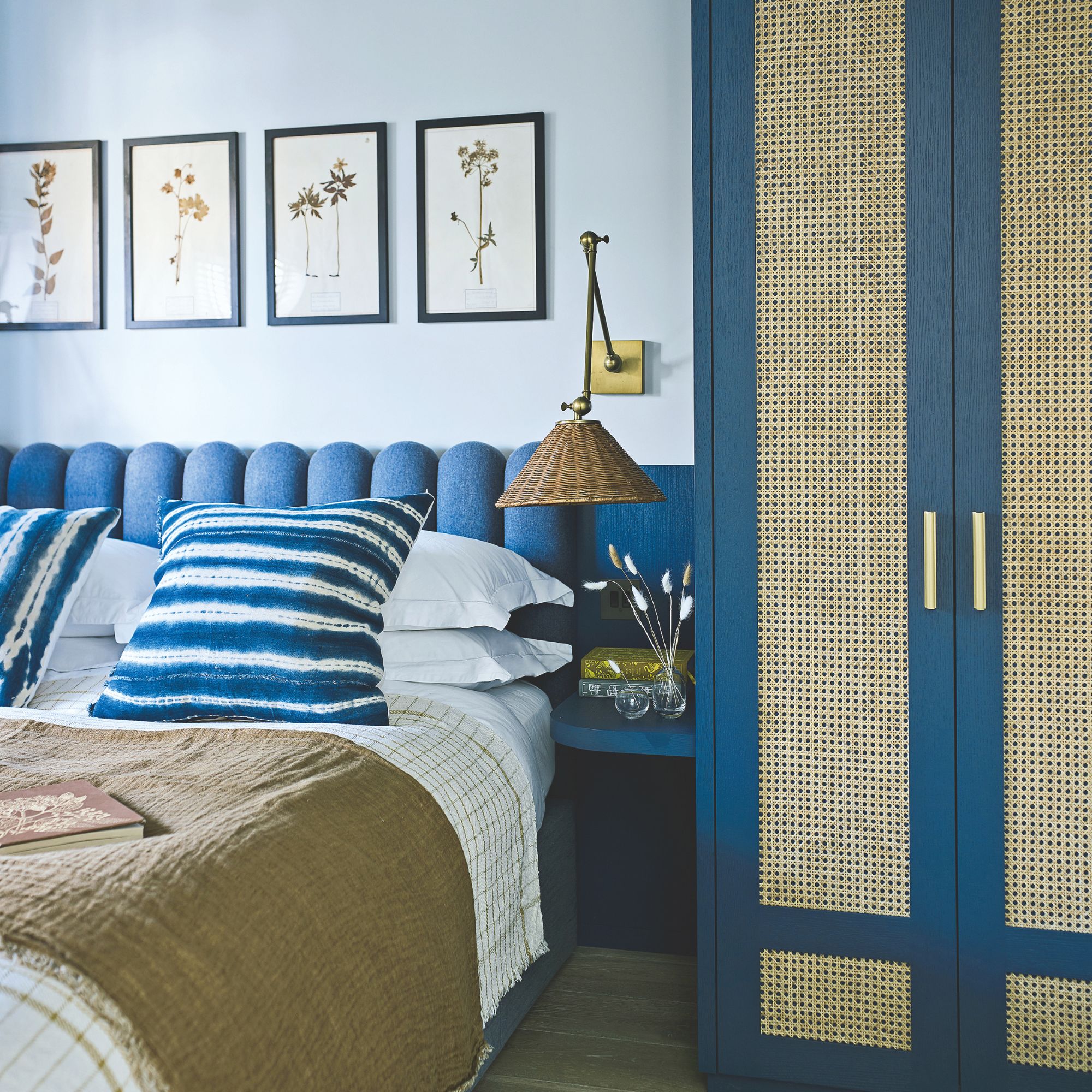 Light blue painted bedroom with a dark blue headboard behind the bed, and dark blue wardrobe next to it