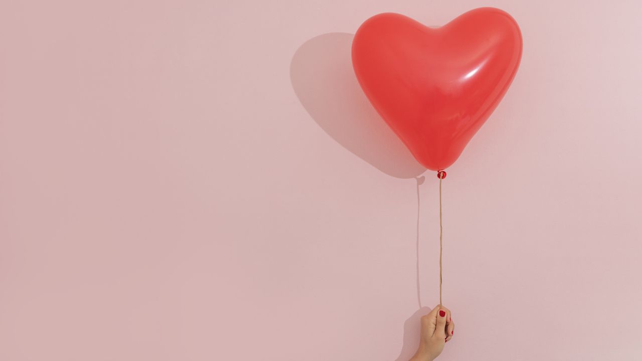 red heart-shaped balloon on pink background 