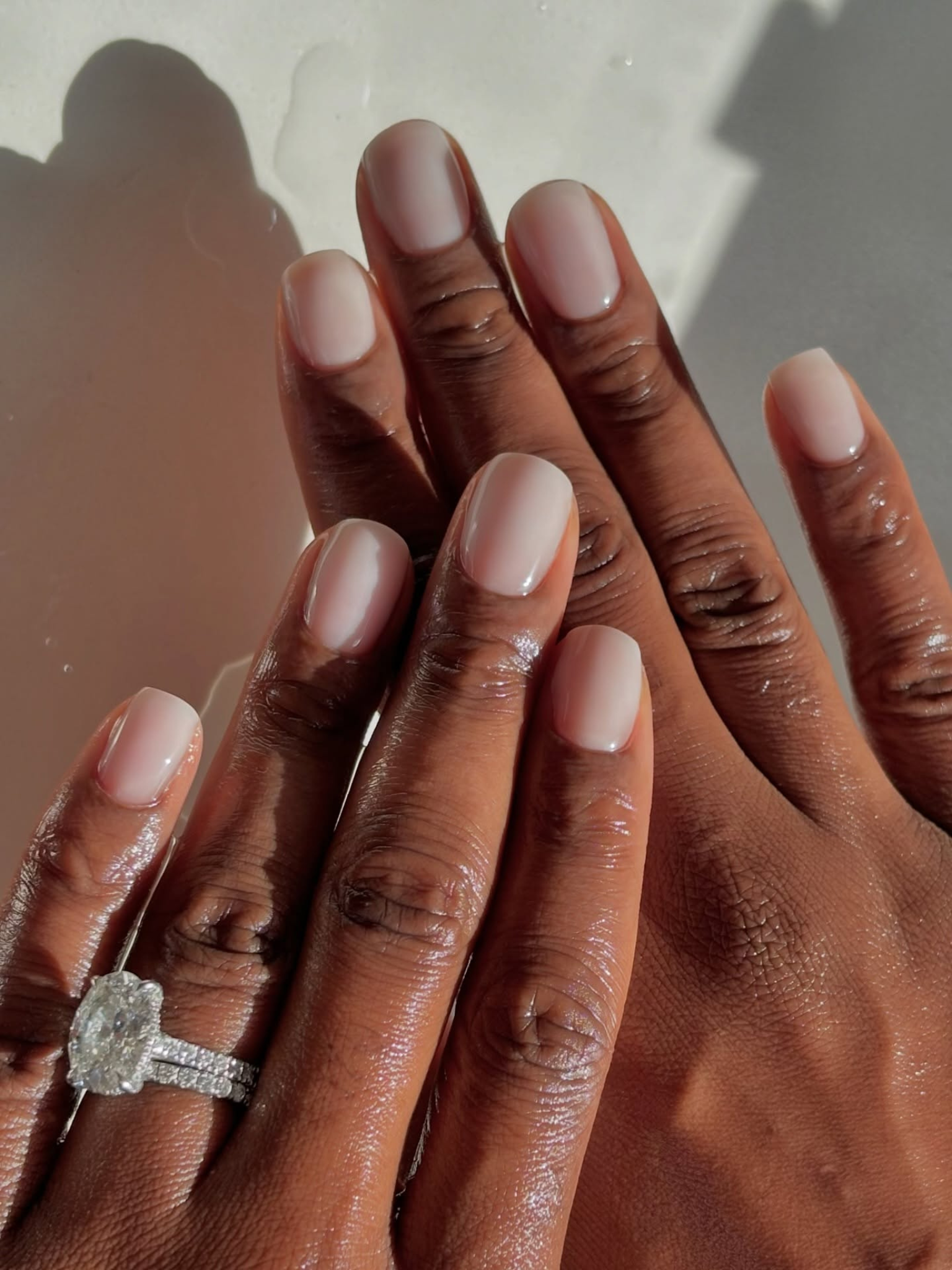 A very pale cool pink shade on short square nails.