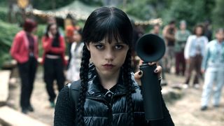 Wednesday Addams holding a back airhorn and looking unimpressed in Wednesday season 2