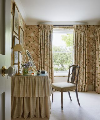 An example of dressing table ideas showing a dressing room in neutral palette with floral curtains and wallpaper