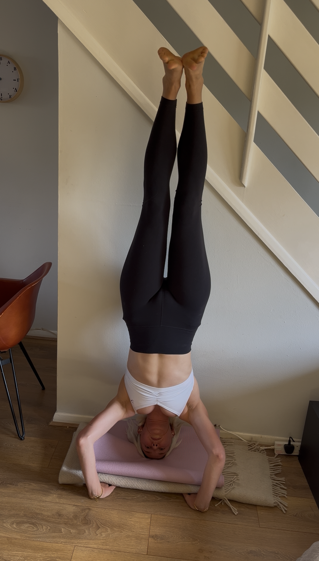A woman practicing a tripod headstand against a wall