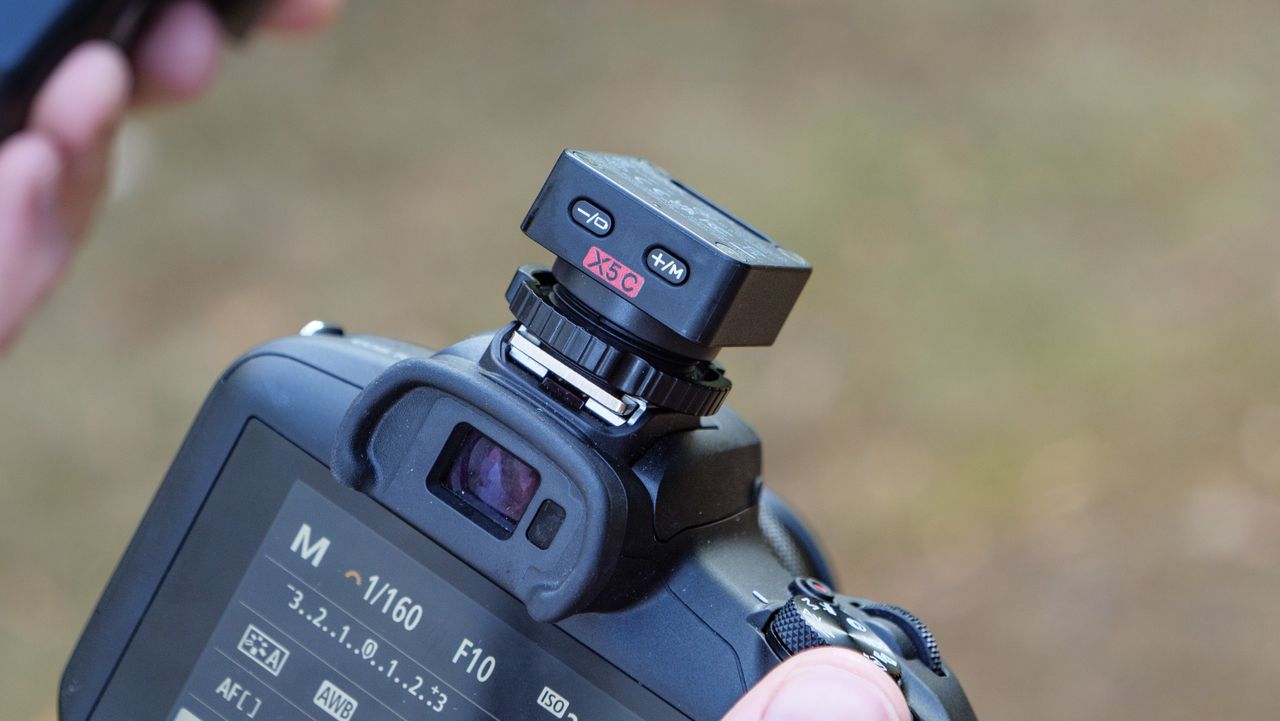 Close up of the Godox iT32 camera flash's X5 remote trigger attached to a Canon camera, held by photographer and TechRadar's Cameras Editor Tim Coleman