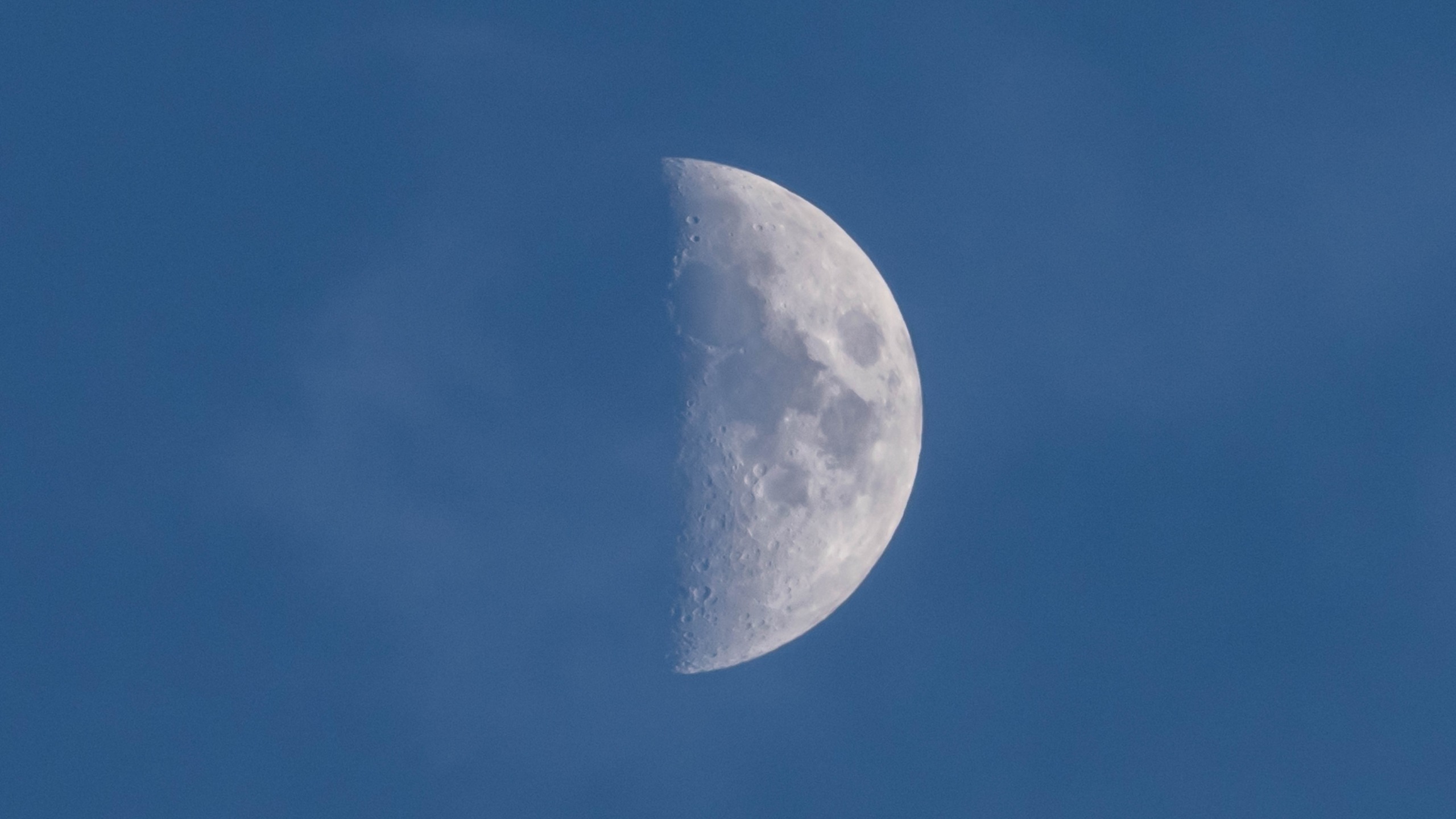 a half illuminated moon in a daytime sky.