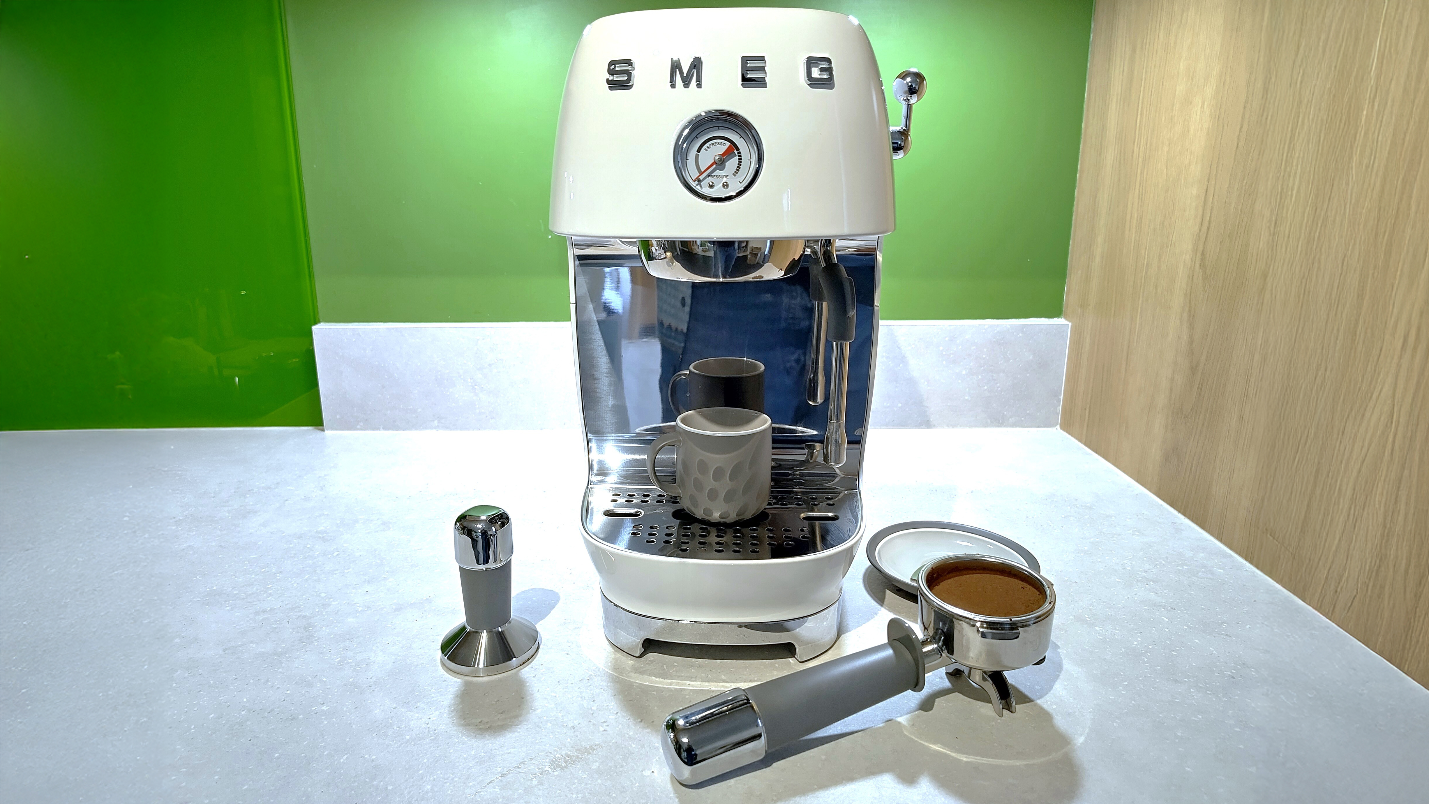 Smeg ECF03 espresso machine with espresso cup, portafilter, and tamper
