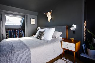 Jason Traves house: Loft bedroom with deep grey walls, upholstered grey bed and mid-century teak side table