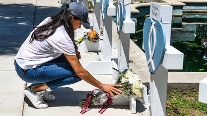 Meghan Markle, the wife of Britain's Prince Harry, places flowers as she mourns at a makeshift memorial outside Uvalde County Courthouse in Uvalde, Texas, on May 26, 2022. - Grief at the massacre of 19 children at the elementary school in Texas spilled into confrontation on May 25, as angry questions mounted over gun control -- and whether this latest tragedy could have been prevented. The tight-knit Latino community of Uvalde on May 24 became the site of the worst school shooting in a decade, committed by a disturbed 18-year-old armed with a legally bought assault rifle.