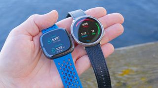 Close up of the Amazfit Active 2 smartwatch next to the Fitbit Sense 2 with each showing the total step count for the day