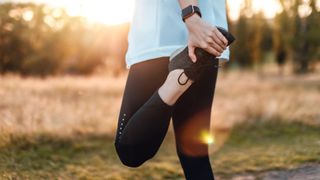 Exerciser performing a standing knee stretch for knee strengthening exercises