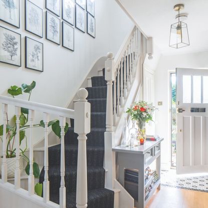 White hallway and staircase with a gallery wall up the stairs