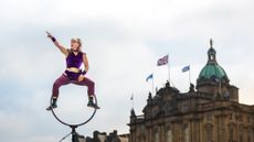 Street acrobat performer resting on a pole with Edinburgh city in the background