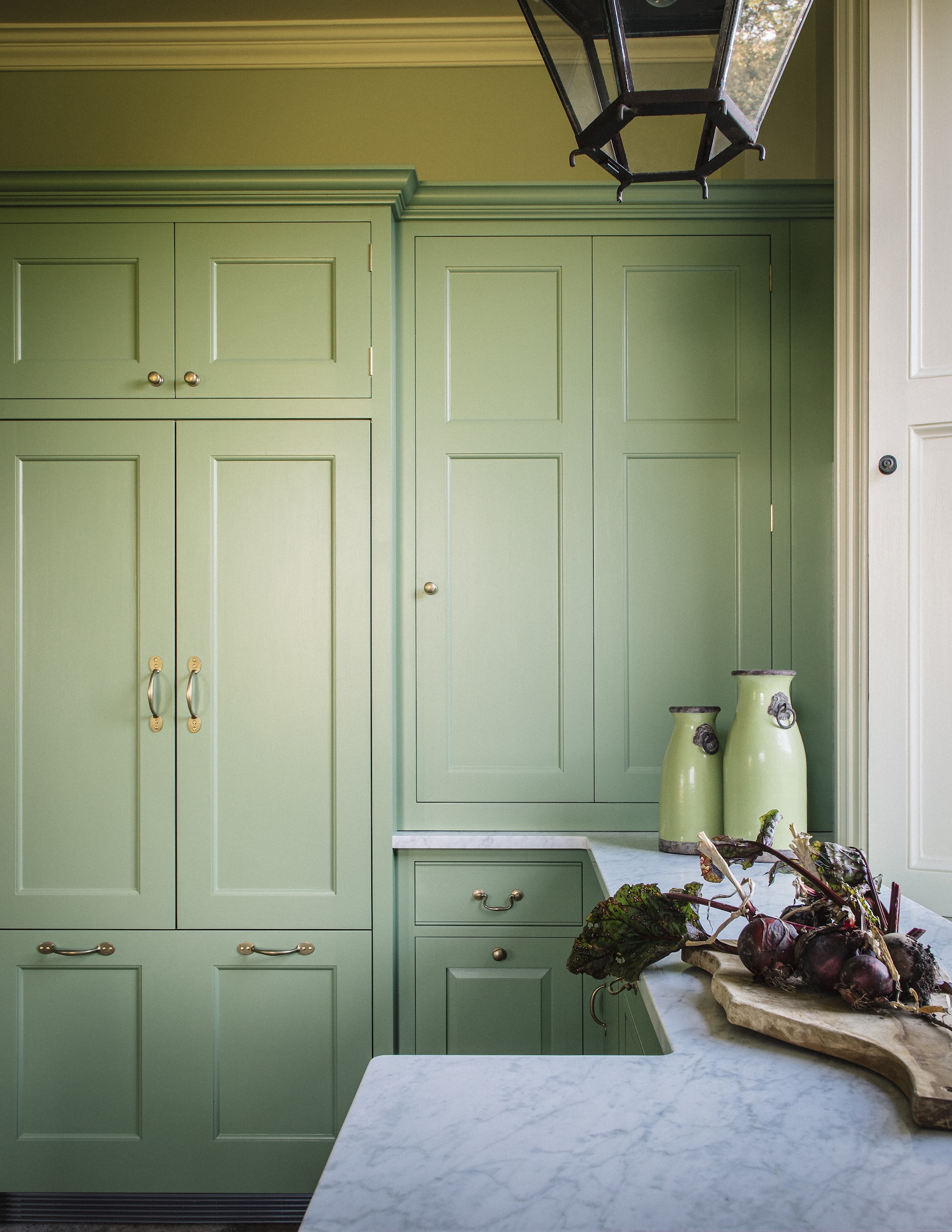 An apple green kitchen with a staggered marble countertop