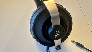 Close ups of the Final DX3000CL with a hi-res digital audio player, showing the ear cups, arm and screen on the player, all on beige background