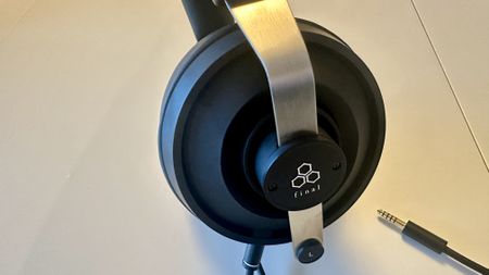 Close ups of the Final DX3000CL with a hi-res digital audio player, showing the ear cups, arm and screen on the player, all on beige background