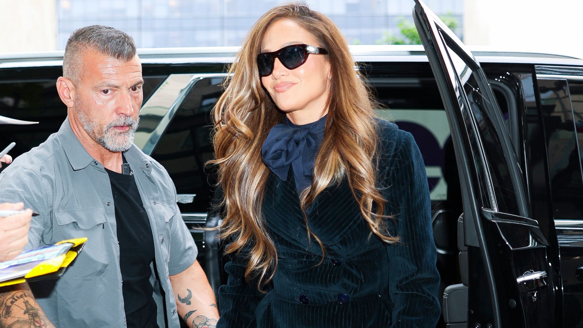 Jennifer Lopez steps out of a car wearing lace footless tights with a velvet tuxedo minidress and a Hermes bag.