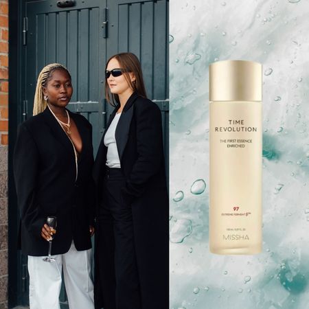 two women standing on the street next to a light blue background with a tan bottle of skincare 