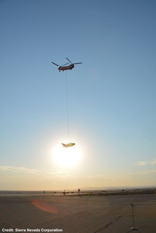 A test model of the Dream Chaser spaceplane rides into the air with help from a Columbia 234-UT helicopter.