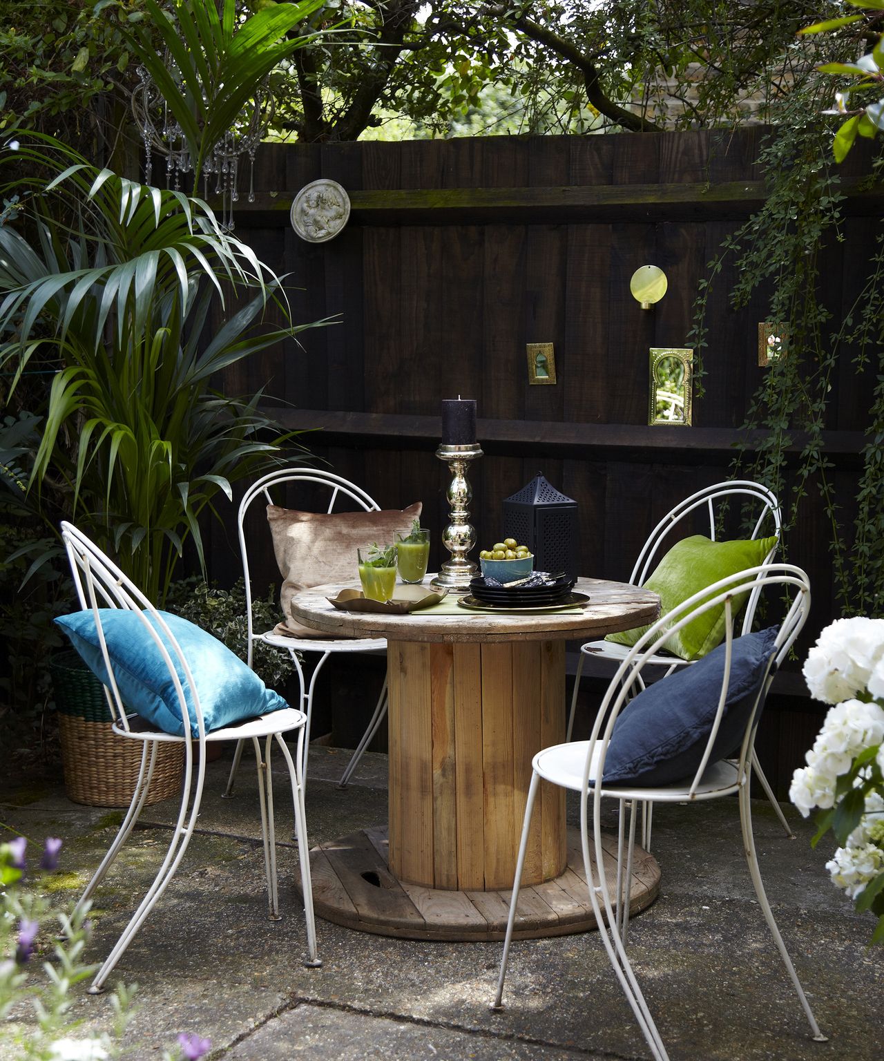 A ciruclar table and chairs in front of a black fence in a Moroccan style courtyard