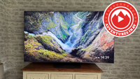 A TCL TV on a wooden media unit with an Adventures in AV logo in the top right corner