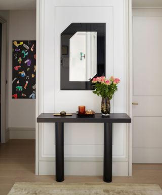 Black mirror over console table in entrance hall.