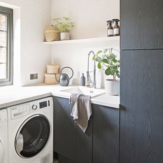 Corner of kitchen with washing machine, sink and shelving