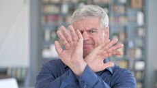 An older man has hands up and crossed as if to say, "No, let's not go there."