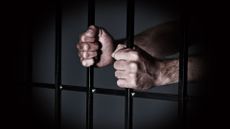 A man holds prison bars 