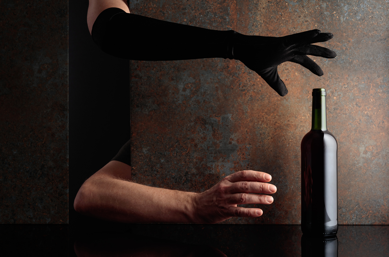 Two hands reaching for a bottle of wine