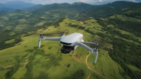 Potensic Atom 3 beginner drone in flight over green landscape