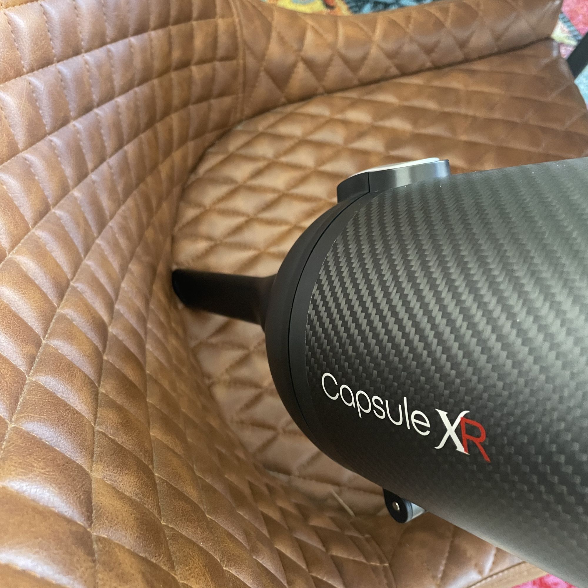 Using the handheld section of the Halo Capsule XR Cordless Vacuum Cleaner to vacuum brown padded chairs