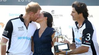 Nacho Figuares of Sentebale St. Regis presents the Sentebale Polo 2018 trophy as Meghan Duchess of Sussex and Prince Harry Duke of Sussex kiss after the Sentebale Polo 2018 held at the Royal County of Berkshire Polo Club on July 26, 2018 in Windsor, England. (Photo by Chris Jackson/Getty Images)