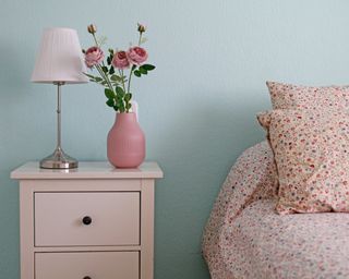 Cozy bedroom with pink bedside drawers, pink vase, pink flowers, pink lampshade and pink bedsheets