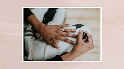 Image of woman painting her nails with a terracotta nail polish, on a muted pink nail polish