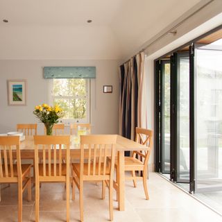 Open bifold doors off a dining area, with a wooden table and chairs