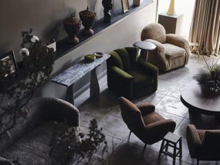 A modern design showroom features lots of 1970s-inspired soft armchairs and couches, along with marble and wooden tables, plants, and other accessories.