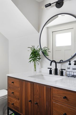 A modern bathroom with wooden cabinetry and white marble vanity