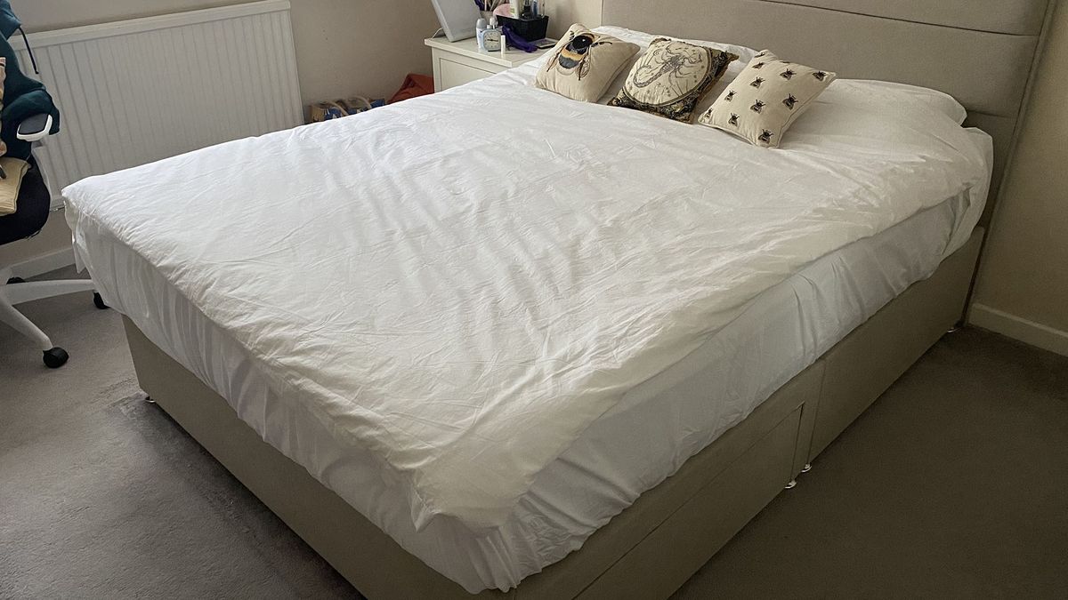 A queen size Siena Memory Foam Mattress on a divan bed frame in our reviewer's bedroom. The mattress is dressed in white bedding with a duvet and two pillow, plus three decorative cushions