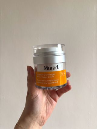 Mica Ricketts sosteniendo un bote de crema reparadora de barrera de noche Murad Essential-C