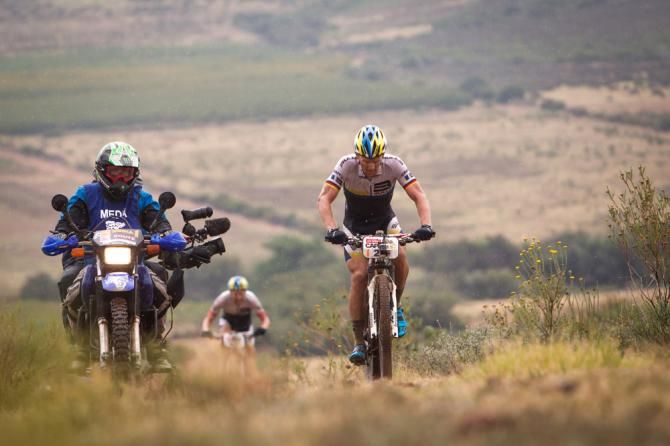 Karl Platt of Team Bulls rolls along accompanied by a camera moto during Cape Epic stage 1
