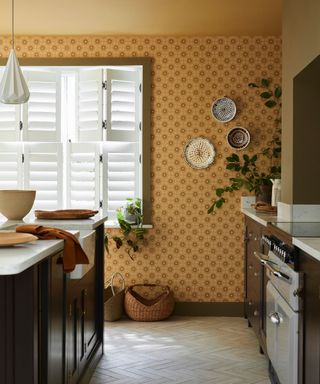 A brown kitchen with a small-scale print yellow wallpaper on one wall