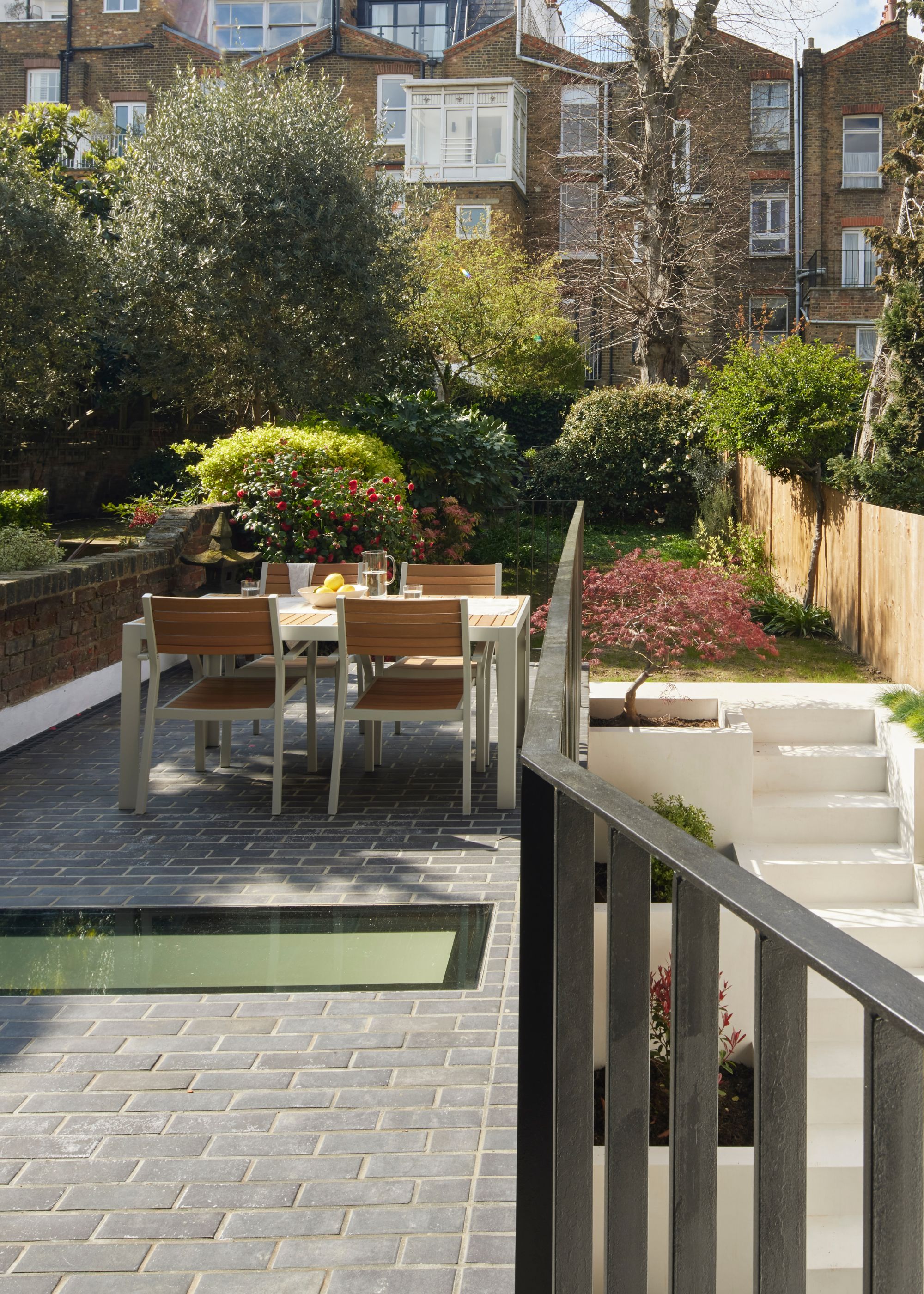 The upper section of the patio which has a skylight on the floor (looking into the kitchen) as well as outdoor patio furniture such as a dining table and chairs