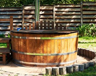 hot tub with small round decking and log fence
