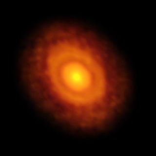 ALMA's radio image of the star V883 Orionis and its disk of gas, dust and debris — a precursor of planet formation. The water snow line is visible as a ring around the disk — the first dark ring after the central brightness of the star — at about the average distance Pluto lies from the sun.