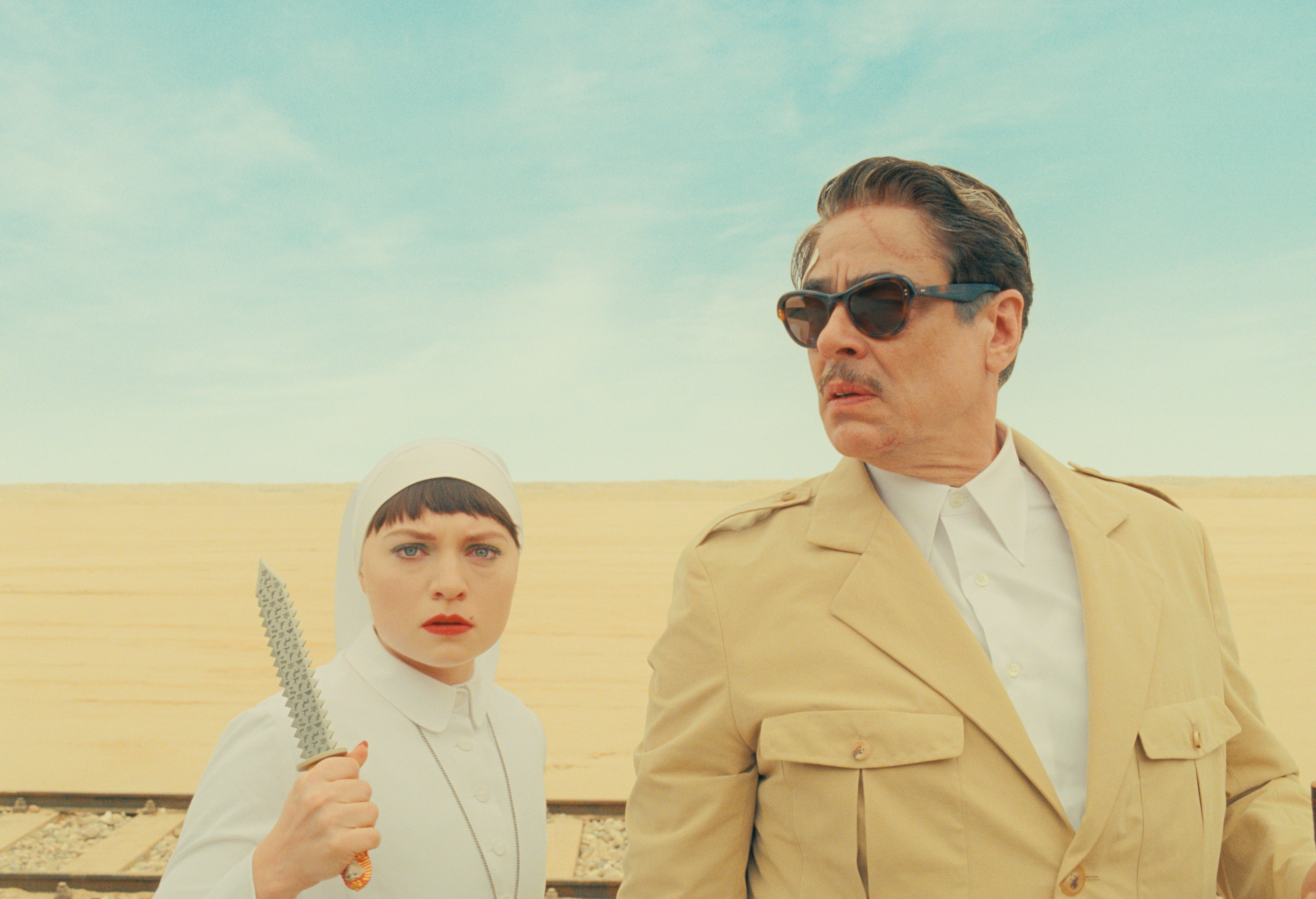 mia threapleton as lisel wearing a nun outfit and holding a knife and standing next to her father zsa zsa kordan played by benicio del toro in the desert