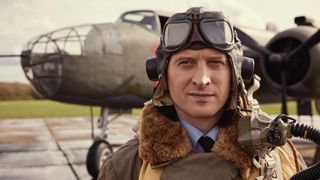 Nicholas Ralph in a flying helmet as James stands in front of a plane in All Creatures Great and Small