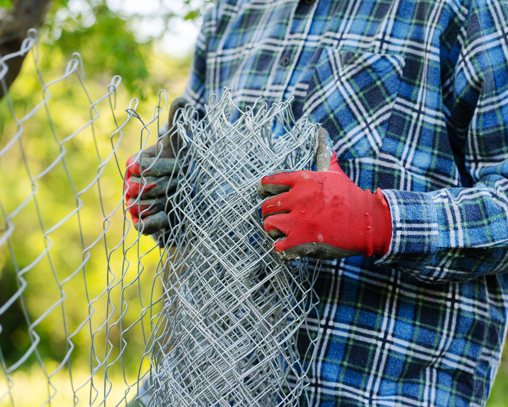 Close up on midsection of unknown man holding protective chain link diamond wire fence